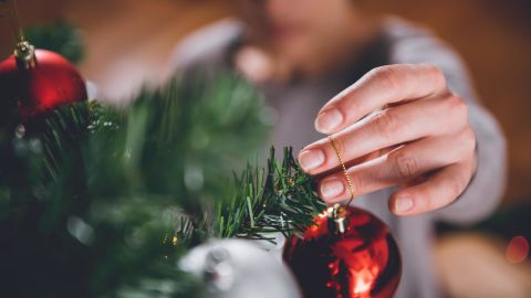 Woman in brown sweater decorating christmas tree 