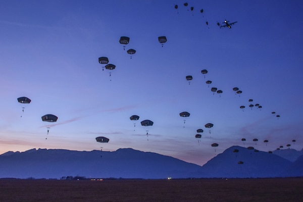 Soldiers conduct a night jump with the Dolomite Mountains in the distance.