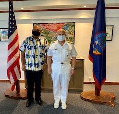 CNO Gilday and Acting Guam Governor pose for a photo in front of Guam and US flags.