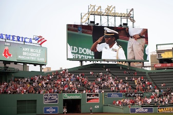 Lt. Cmdr. Lauren Cherry, flag aide to Chief of Naval Operations Adm. Mike Gilday, salutes the before a Red Sox baseball game at Fenway Park, Boston.
