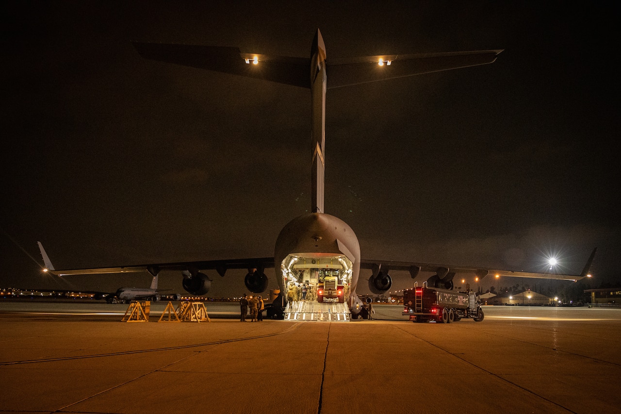 Personnel surround a forklift in the cargo bay of a large aircraft.