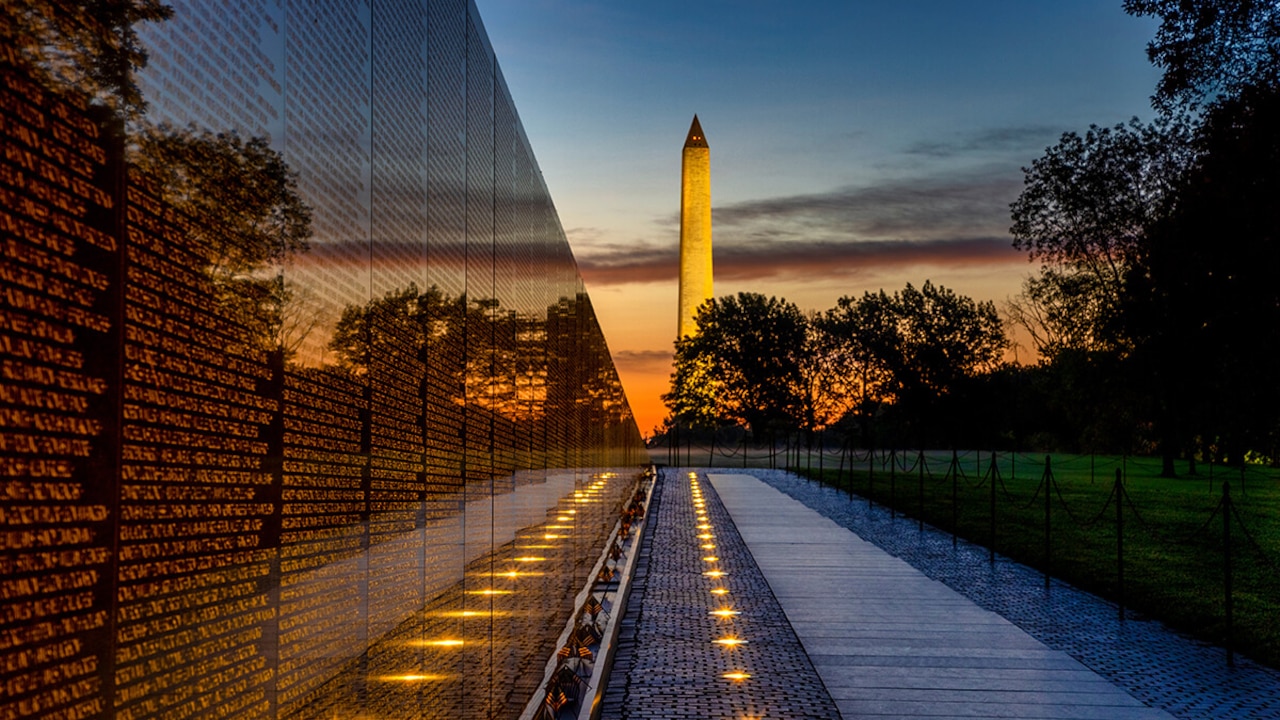 The Vietnam Veterans Memorial wall is seen with a view toward the Washington Monument at sunset.