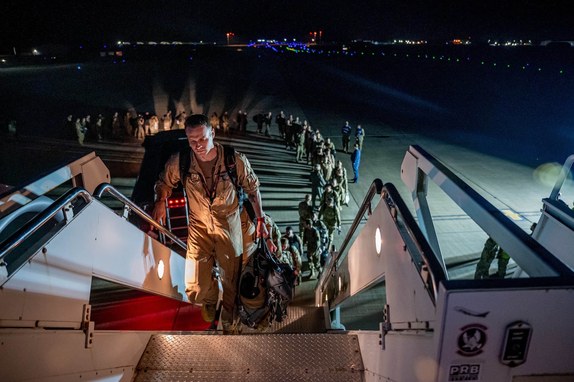 Airmen forming line walking up stairs to board Aircraft