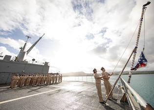 Chief petty officers aboard USS Emory S. Land (AS 39) raise the national ensign at Naval Base Guam.