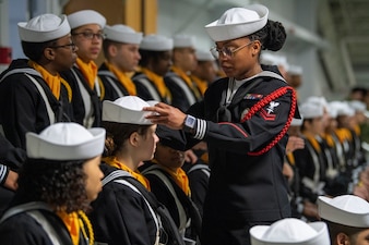 HM2 Ashley Thornton fixes a recruit's cover before a Pass in Review graduation.