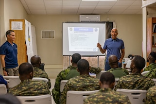 A man instructs a group of military students in a classroom.