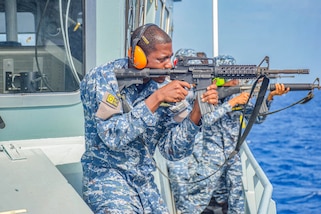 A Barbados Coast Guard member shoots a rifle.