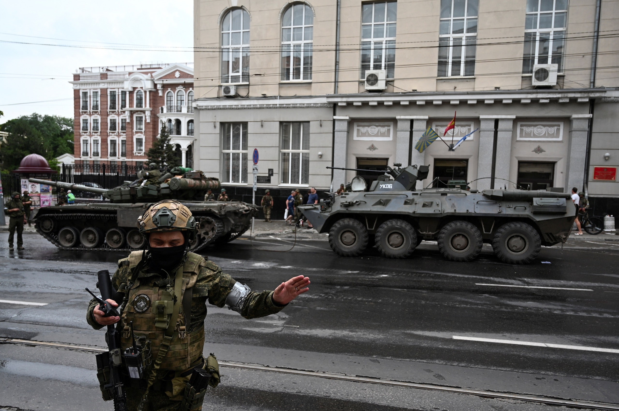 A fighter from the Wagner Group in military fatigues stands before two tanks in the streets of RostovonDon Russia.