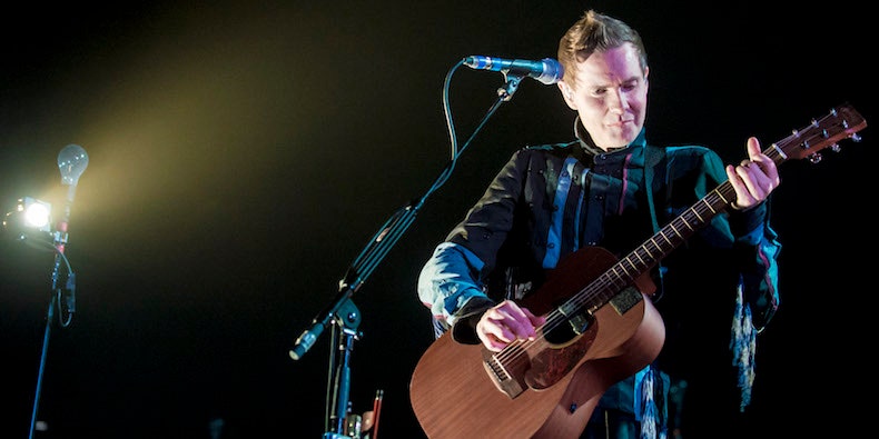 Jonsi of Sigur Ros playing a guitar onstage.