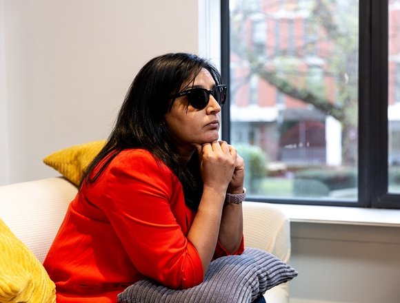 Renu wearing glasses while sitting on a sofa.