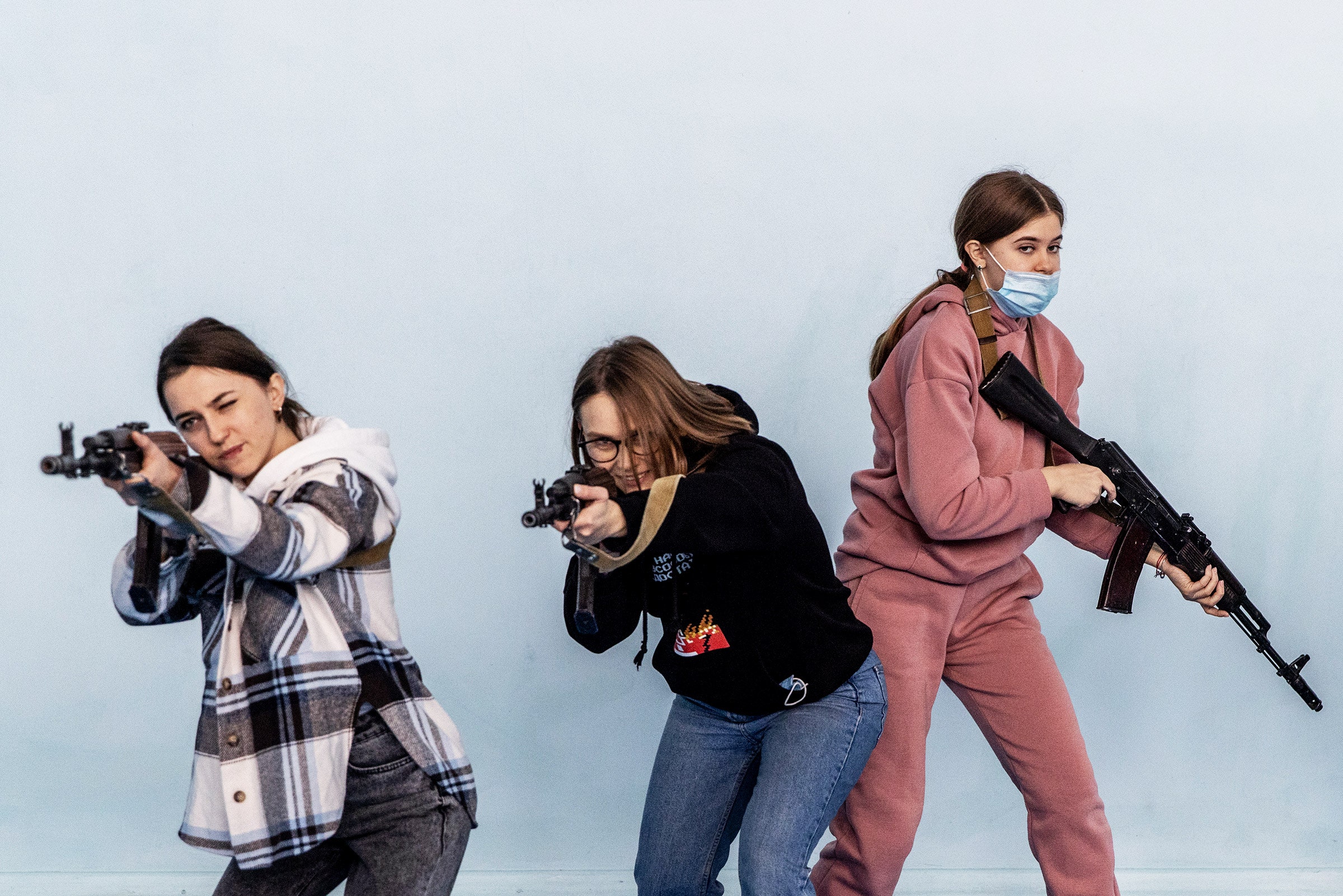 Three civilians holding guns in a beginners combat and survival training course in Kyiv Ukraine