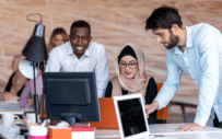 People gathered around table looking at computer