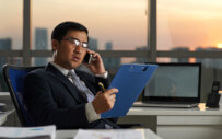 Man looking at clipboard while on the phone