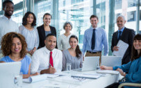 group of coworkers posing for a picture around a large table at the office