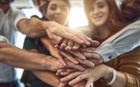 A group of people places all of their hands on top of one another.