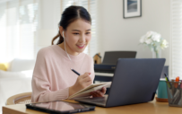 A young professional onboards with her new team remotely on a laptop.