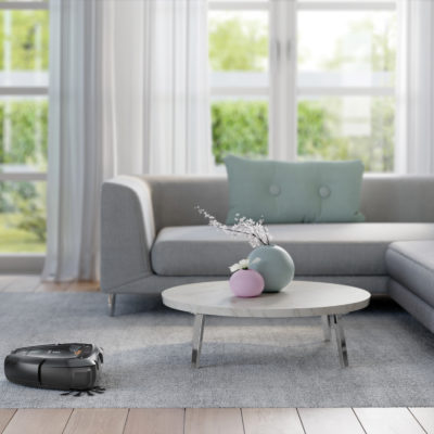 A Pure i9 cleans a rug and flooring while navigating a table and sofa.