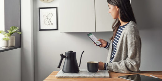 Woman interacts with Microsoft 365 on a phone in her kitchen