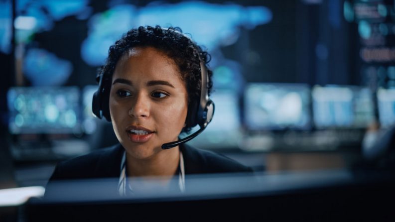 A young female security specialist on call consults the digital screen in front of her.