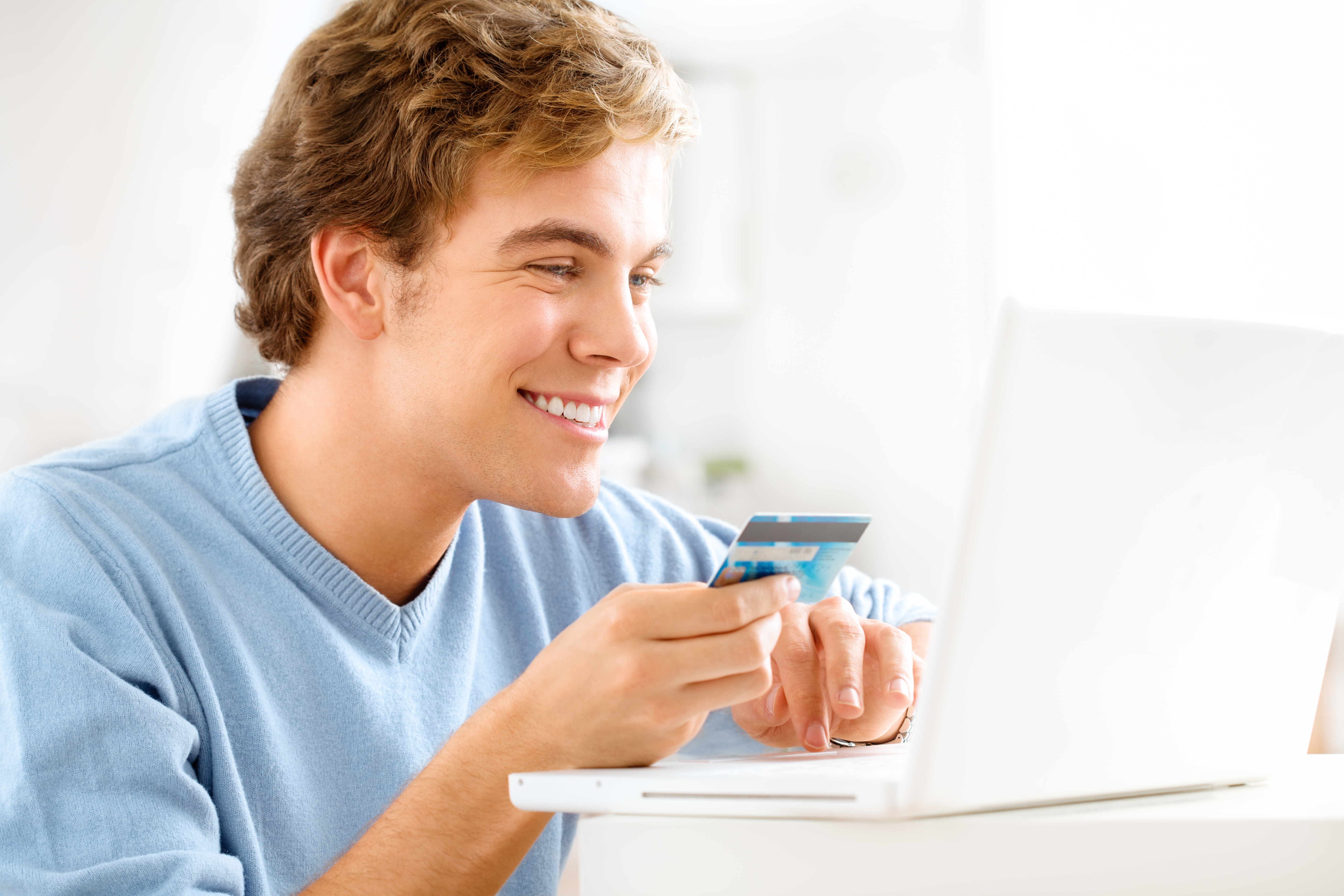 A young man uses his credit card to shop online.