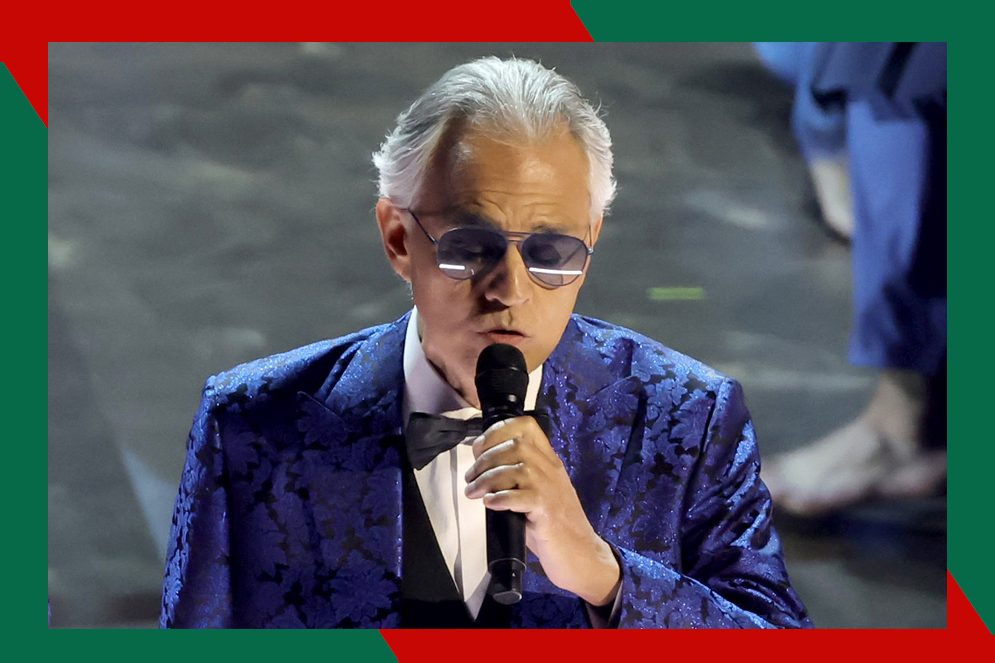 Andrea Bocelli sings with a microphone in hand.