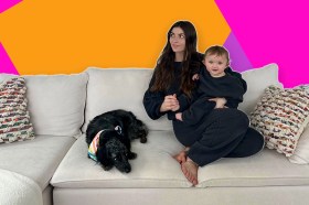 A woman and a baby sitting on a couch with a dog