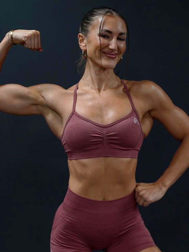 Hayley Madigan, a fitness trainer, poses in a sports bra and shorts with her biceps flexed.