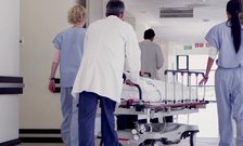 Medical professionals push a patient on a stretcher through a hospital