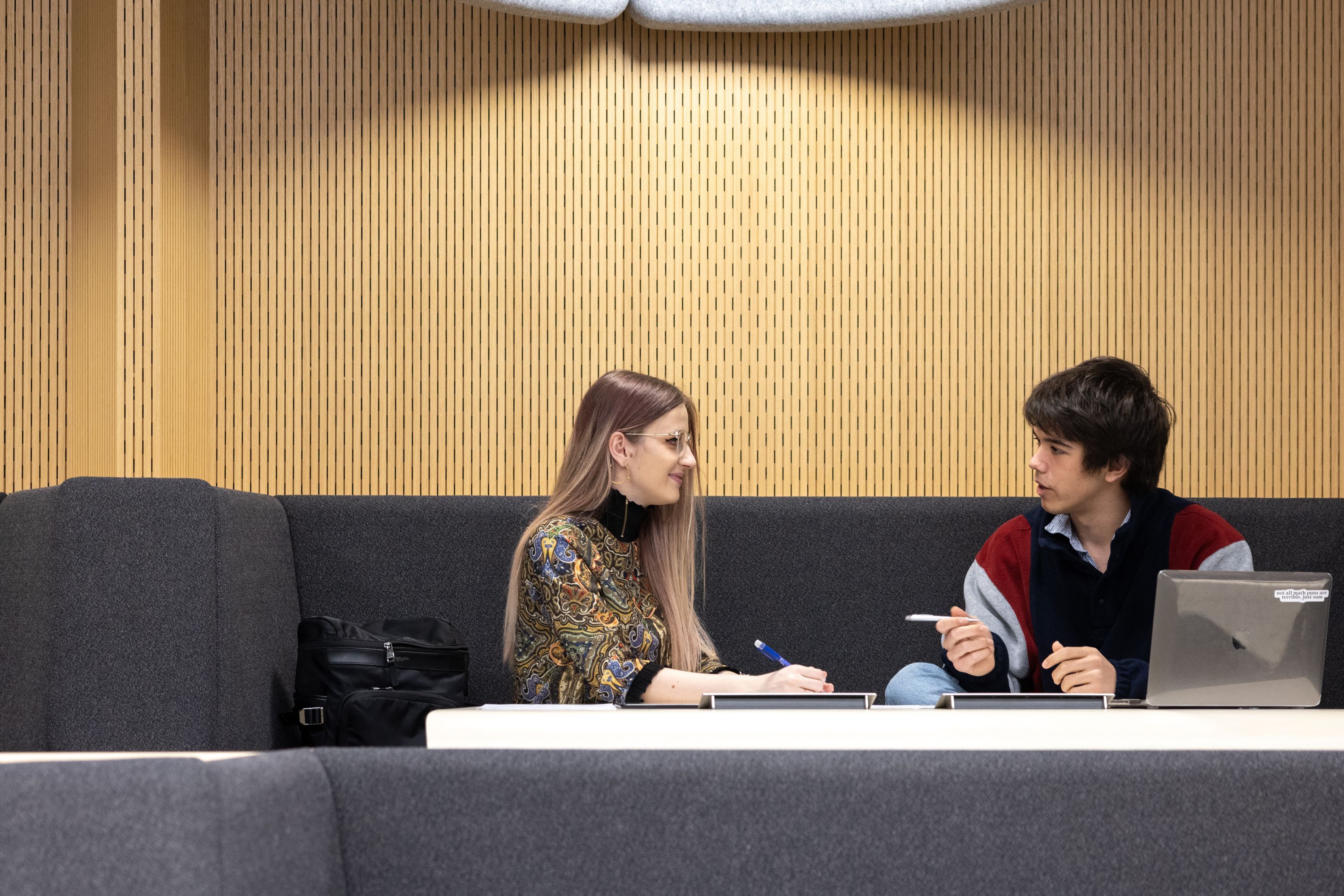 Two students sat chatting near a laptop