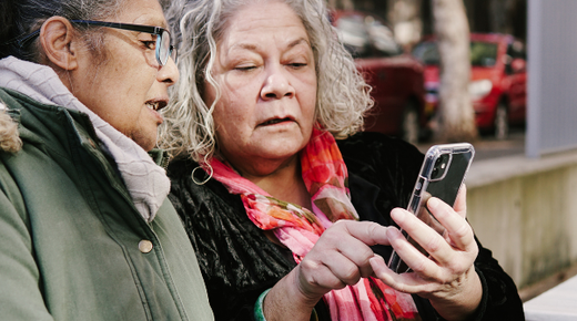 Two middle-aged women looking at something on a mobile phone together.