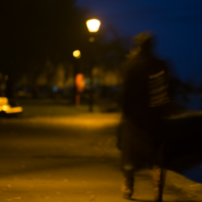 A blurred image shows a woman walking alone at night.