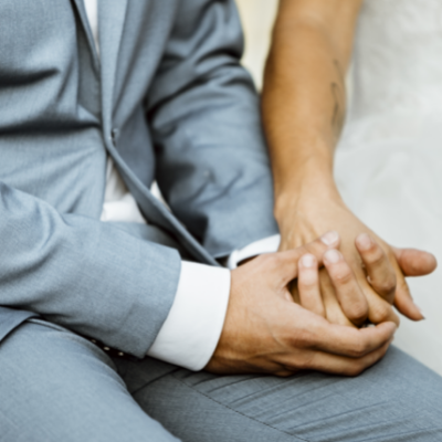 A couple who have just got married sit together holding hands.