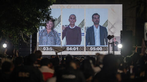 Des personnes regardent sur un écran géant le débat entre les candidats à la présidentielle. De gauche à droite : Xochitl Galvez, Claudia Sheinbaum et Jorge Alvarez Maynez. Mexico, Mexique, 28 avril 2024.