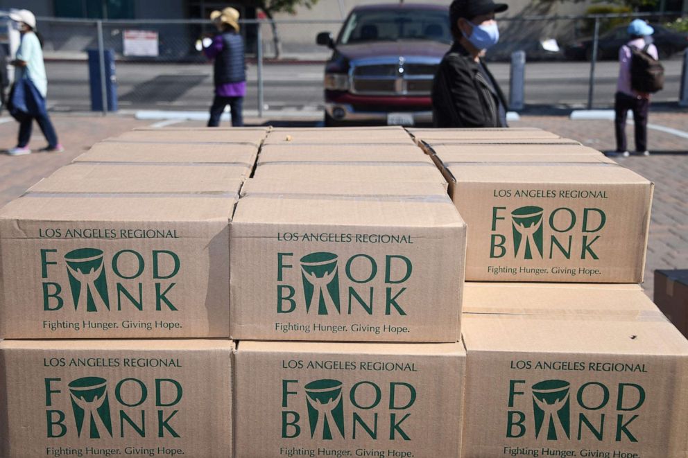 PHOTO: Boxes of food are stacked next to people waiting in line at a walk-up food distribution bank for people facing economic hardship or food insecurity, in a church parking lot in Los Angeles, Aug. 10, 2020 amid the COVID-19 pandemic.