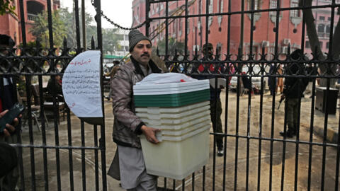 A man carries election-related material at a distribution centre in Lahore, Pakistan on February 7, 2024, one day before the opening of the polls.