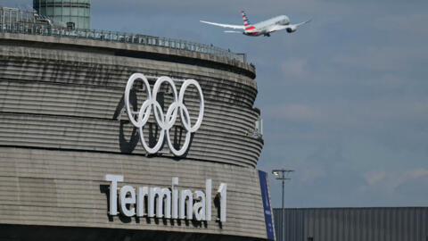 This photograph taken in Roissy-en-France on April 23, 2024, shows the Olympic rings on the Roissy - Charles de Gaulle Airport Terminal 1 as an aircraft takes off.