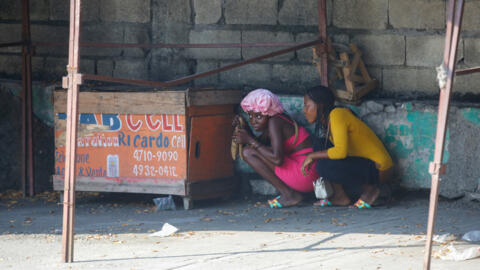 Des femmes se mettent à l'abri lors d'une fusillade entre la police et des membres de gangs à Port-au-Prince, Haïti, le 1er mars 2024.