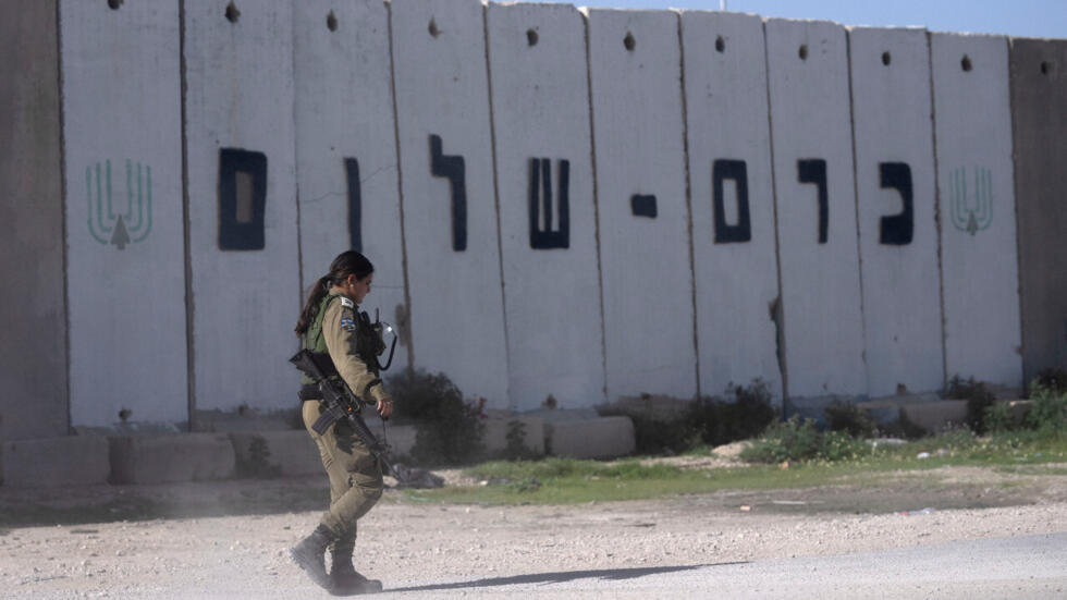 Une soldate de l'armée israélienne patrouille devant le point de passage de Kerem Shalom, entre Israël et la bande de Gaza.