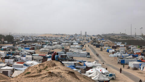 Displaced Palestinian children sit on a dune overlooking their tent camp in Rafah in the southern Gaza Strip by the border with Egypt on April 26, 2024.