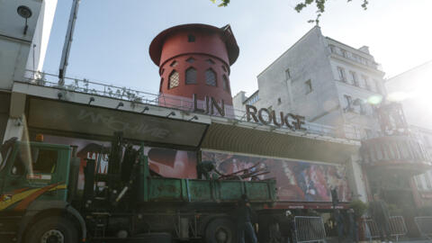 Workers in front of the Moulin Rouge windmill in Paris on April 25, 2024, hours after the blades collapsed overnight.