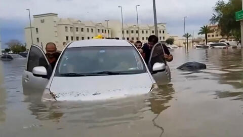 Varios residentes empujan un coche anegado por una calle inundada de la ciudad desértica de Dubai tras las lluvias torrenciales que paralizaron el centro financiero y de ocio del Golfo.