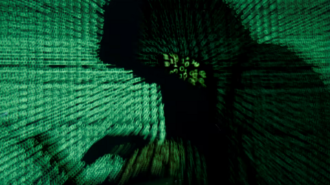 رجل يحمل جهاز كمبيوتر بينما يتم عرض كود إلكتروني في هذه الصورة التي تم التقاطها في 13 أيار/مايو 2017.