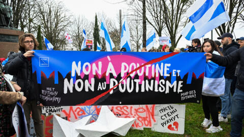 Protesters hold a banner reading "No to Putin, no to Putinism" during a gathering of Navalny's supporters near the Russian Embassy in France, in Paris, on March 17, 2024.