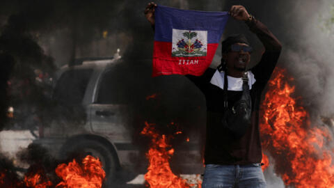 A demonstrator holds up a Haitian flag during a protest against Prime Minister Ariel Henry's government and insecurity, in Port-au-Prince, Haiti March 1, 2024. 