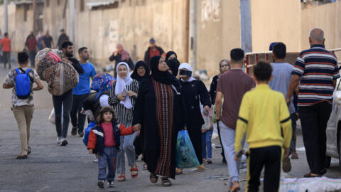 Palestinians carrying their belongings flee to safer areas in Gaza City after Israeli air strikes, on October 13, 2023.