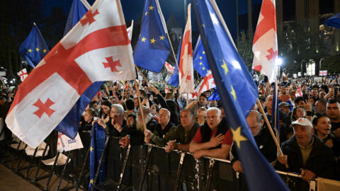Protesters hold Georgian national and European flags during a demonstration outside the parliament building as they protest against a draft bill on "foreign influence" in Tbilisi on April 17, 2024.