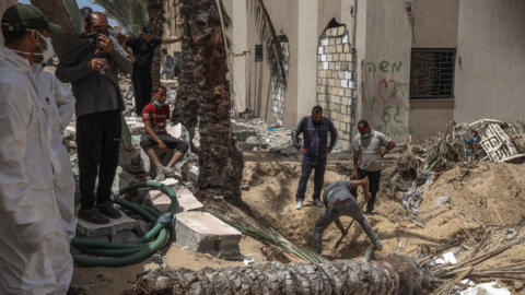 عمال من الصحة في غزة يبحثون عن جثث  في مقبرة جماعية عثر عليها بمستشفى ناصر في خان يونس، 23 أبريل 2024.