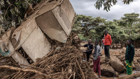 Young men inspect a destroyed car carried by waters in an area heavily affected by torrential rains and flash floods in the village of Kamuchiri, near Mai Mahiu, Kenya on April 29, 2024. 