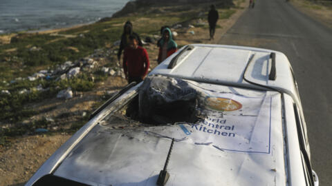 Palestinians inspect a vehicle with the logo of the World Central Kitchen wrecked by an Israeli airstrike in Deir al Balah, Gaza Strip, April 2, 2024.