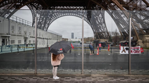 A child stands in front of the Eiffel Tower where a banner informs that the staff of the hugely popular monument is on strike, on February 19, 2024.